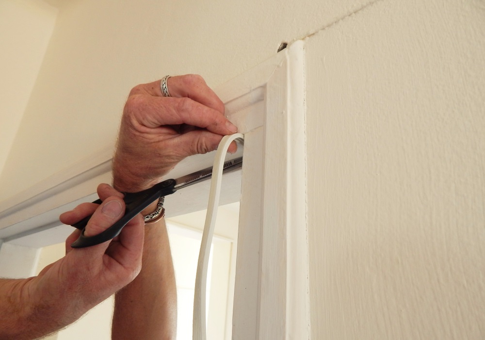 Hands,Affixing,Adhesive,Rubber,Draft,Proofing,To,A,Door,Frame.